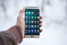 Person hält Handy in der Hand, das Apps auf dem Bildschirm anzeigt